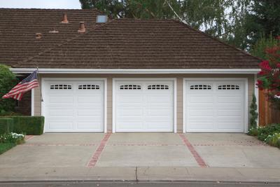 Picture of a three car garage with a concrete driveway with stamped red brick border in Nashua, New Hampshire.