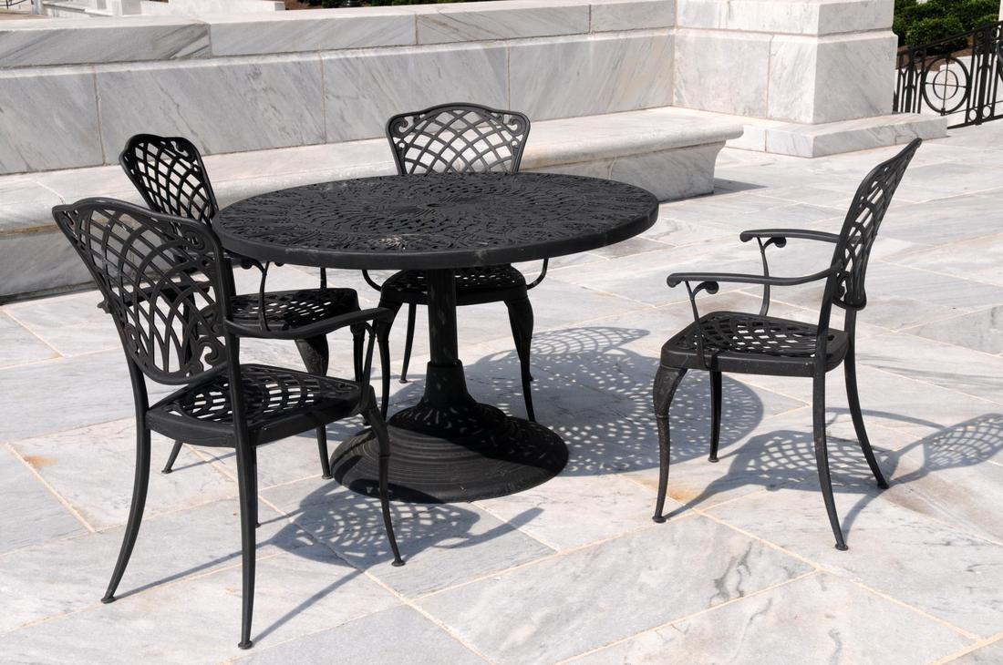 Picture of a stamped concrete patio with black iron table and chairs. Picture was taken in Nashua, NH